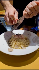 Grating the black truffle over a plate of pasta.